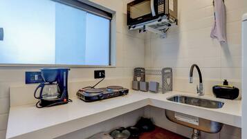 A compact kitchen with a coffee maker, microwave, sink, and various kitchen utensils.