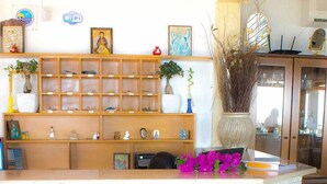Zona de recepción con un mostrador de madera, una encimera de mármol blanco y una estantería con diversos objetos decorativos.