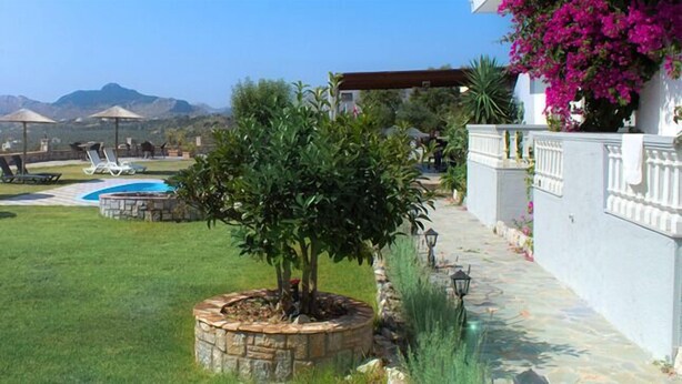 Un espacio exterior bien cuidado con piscina, sillas de descanso y vistas al mar y a las montañas.