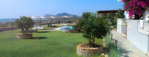 A well-maintained outdoor area with a swimming pool, lounge chairs, and a view of the sea and mountains. - Gardenia Hotel (Rhodes)