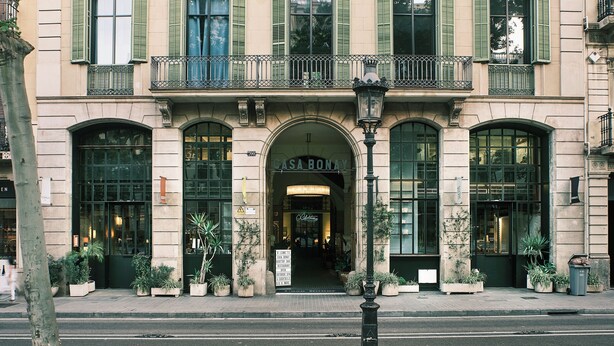 Un edificio de varios pisos con un estilo arquitectónico clásico, que cuenta con balcones con barandillas de hierro forjado, amplias ventanas en arco con contraventanas verdes y una entrada destacada con un letrero que dice 'CASA BONAY'.
