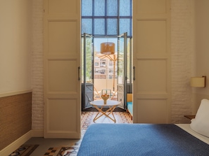 A room with a bed, a small table with chairs, and a view through an open door to an outdoor area with a table and chairs. - Hotel Casa Bonay & Spa (Barcelona)