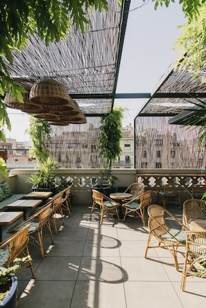 Relax in a shaded patio area with wicker furniture, overlooking the city.
