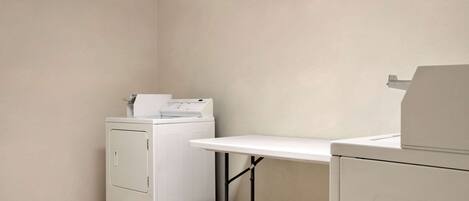 A laundry room with a washing machine, a drying machine, and a table.