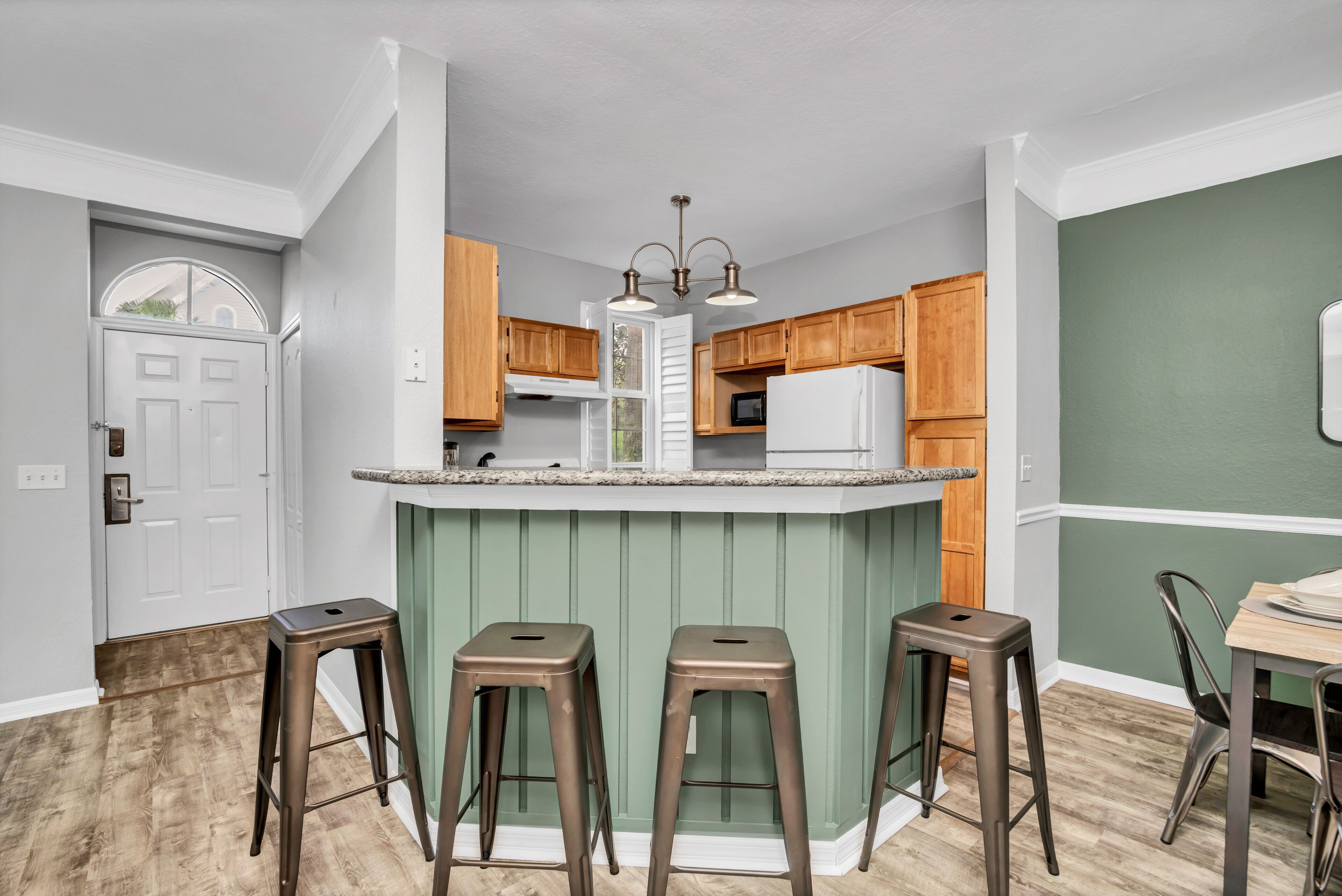 Una cocina con una isla central, armarios de madera y un refrigerador blanco.
