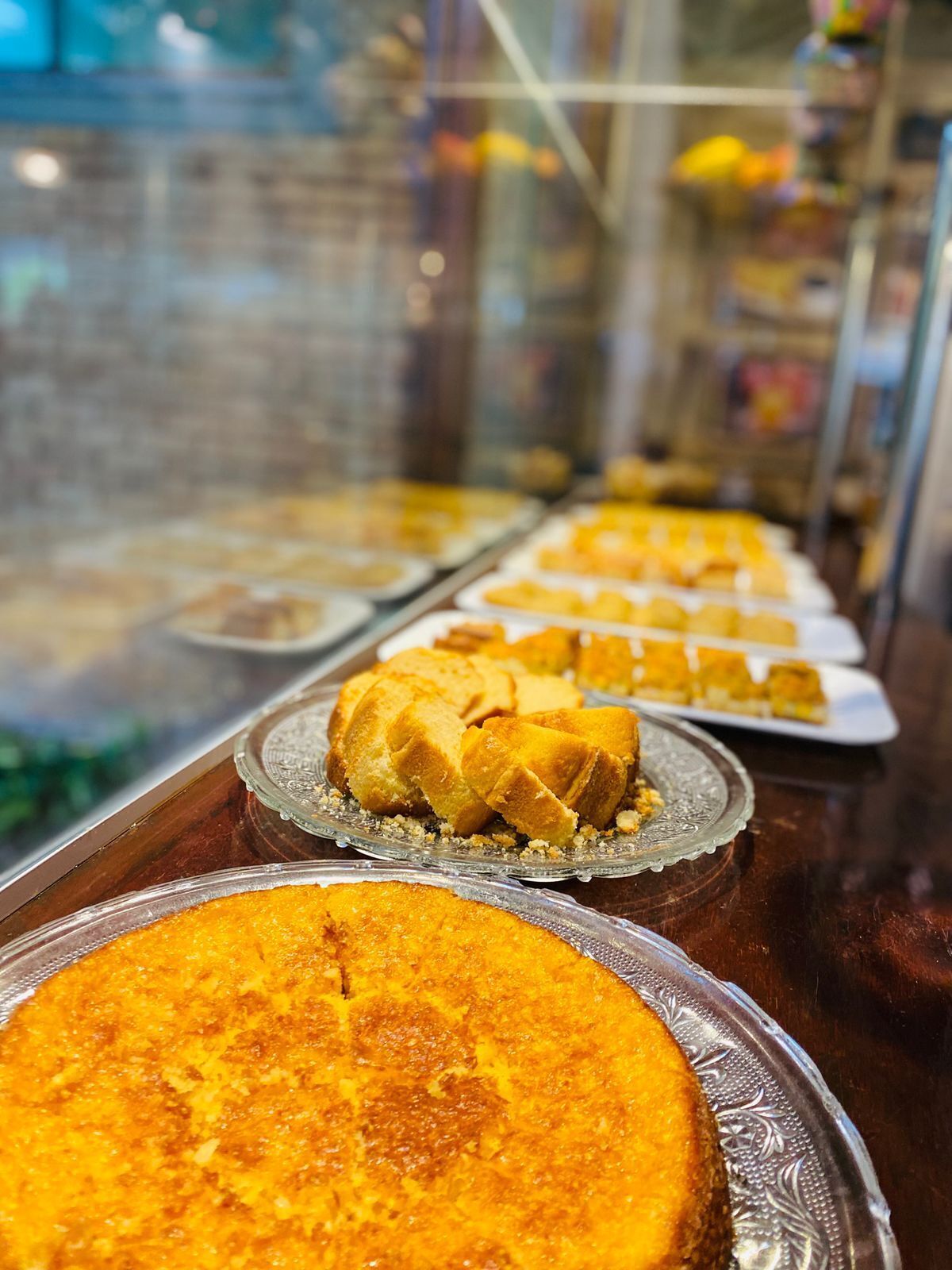 A display case with various baked goods, including a large golden-brown cake and smaller pastries.