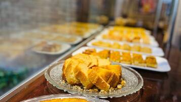 A display case with various baked goods, including a large golden-brown cake and smaller pastries.