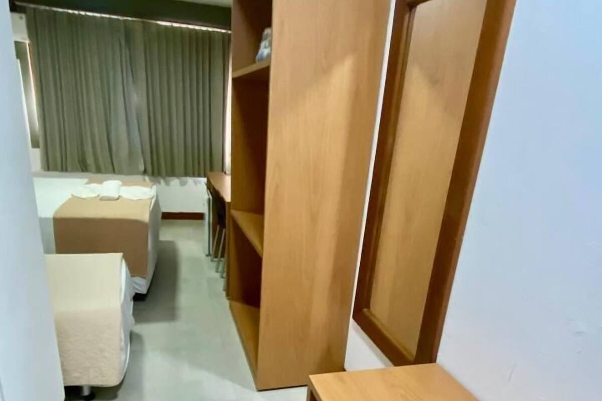 A hotel room with a bed, a wooden bench, and a wardrobe.