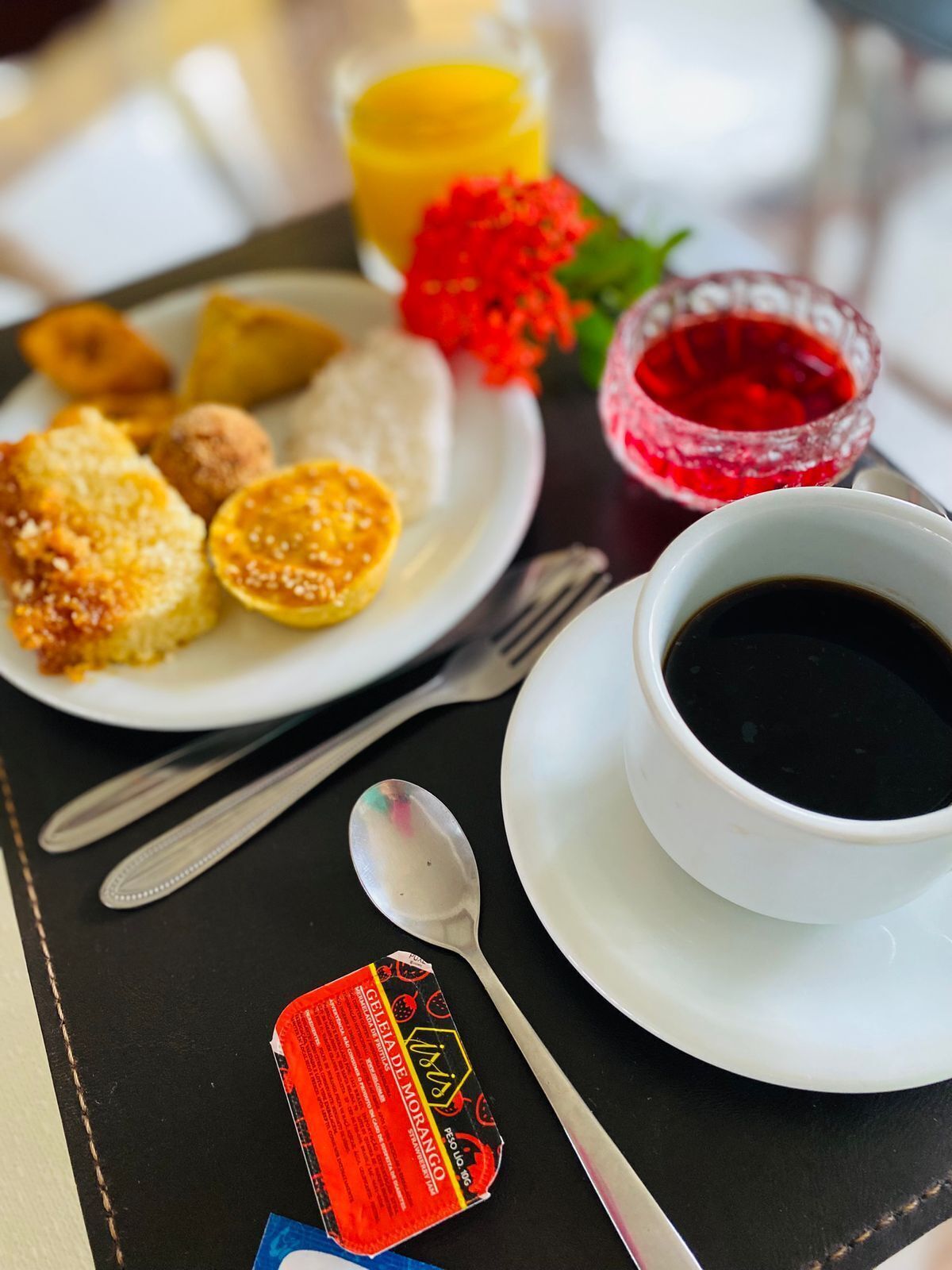 A breakfast tray with various foods, a cup of coffee, and a glass of juice.