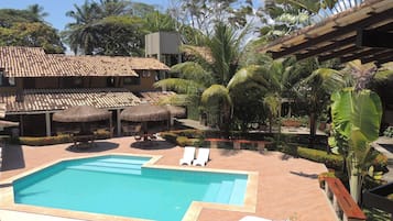 Una piscina al aire libre, sombrillas, sillones reclinables de piscina