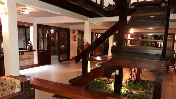 A lobby with a wooden staircase, seating area, and a small indoor garden. - Marinas Pousada (Ilhéus)