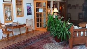 A cozy living room with a large rug, wooden furniture, and a welcome sign. - White Birch Inn (Sturgeon Bay)