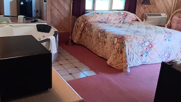 A bedroom with a bed, a desk, a mirror, a dresser, and a window with curtains.