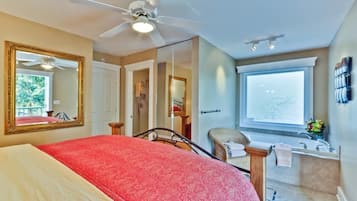 Habitación de hotel con cama, ventilador de techo, ventana grande, baño con bañera y espejo.
