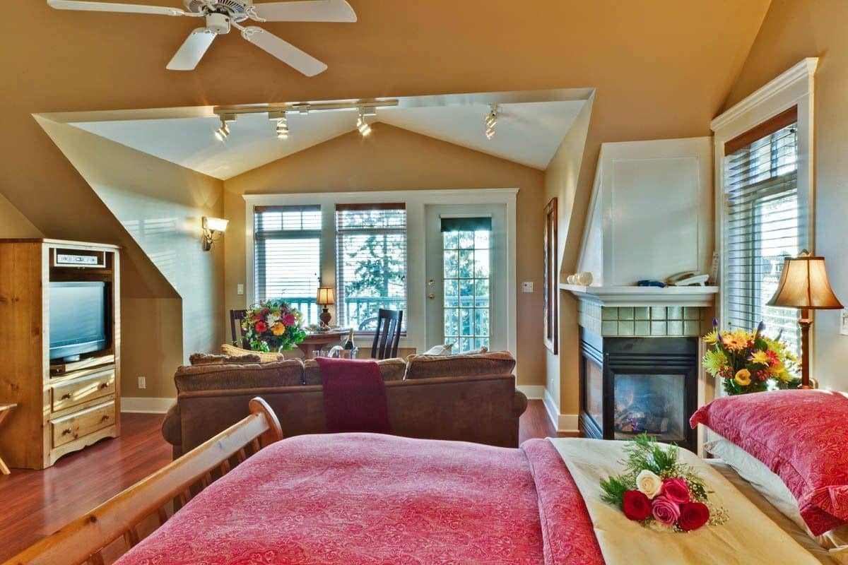 A cozy bedroom with a large bed, a desk, and a fireplace.