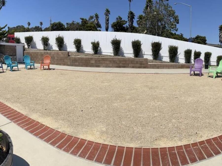 Un área exterior con asientos al aire libre y varias sillas Adirondack dispuestas alrededor de un espacio central de grava, bordeada por un sendero de ladrillo.