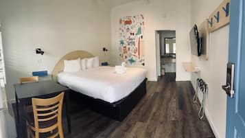 Quarto com cama, escrivaninha, cadeira, televisão e decoração de parede com tema de surf.