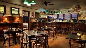 A cozy bar area with wooden furniture, a tap room sign, and a view of the outdoors through large windows. - Belton Chalet (West Glacier)
