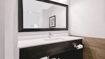 A modern bathroom with a large mirror, a white sink, dark wood vanity, and a towel rack with neatly folded towels.
