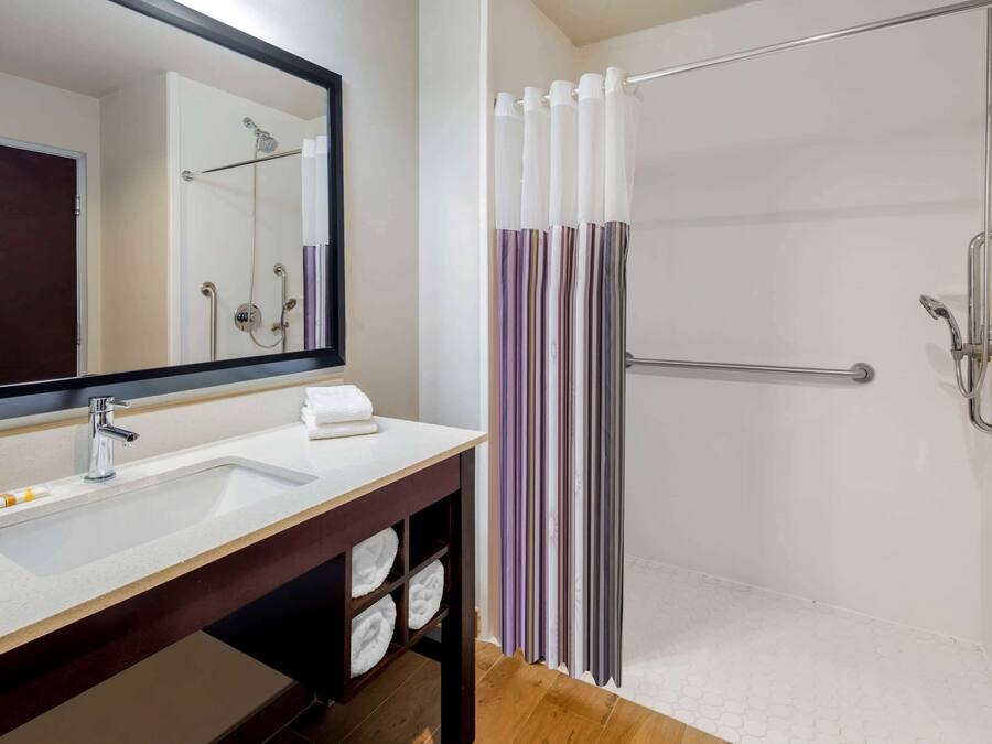 A bathroom with a white sink, a mirror, a shower with a glass door, and a towel rack.