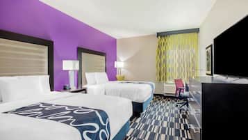 A hotel room with two beds, a desk with a chair, a television, and a patterned carpet.