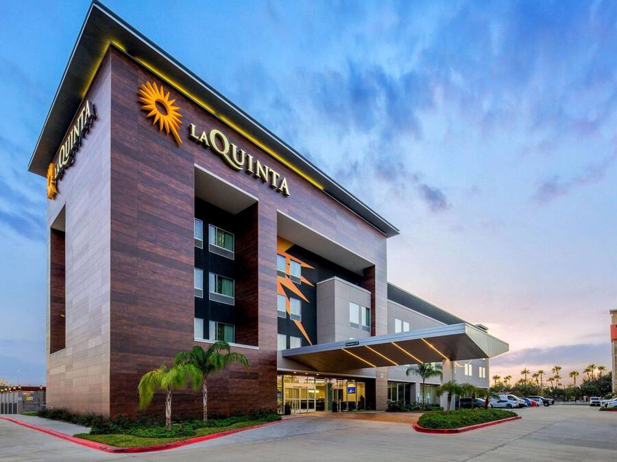 Ein La Quinta Hotel mit modernem Design, das ein auffälliges Sonnensymbol und einen überdachten Eingang zeigt.