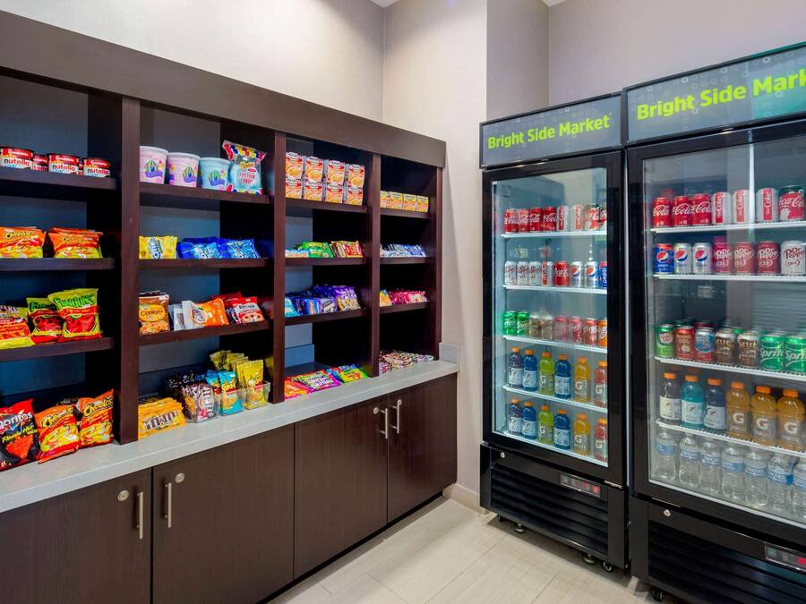 A snack and beverage vending area with multiple shelves stocked with various snacks and a Bright Side Market sign above two beverage dispensers.