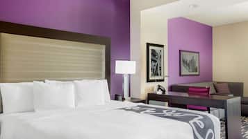 Ein Hotelzimmer mit Bett, Schreibtisch, Stuhl, Lampe und einer Couch.