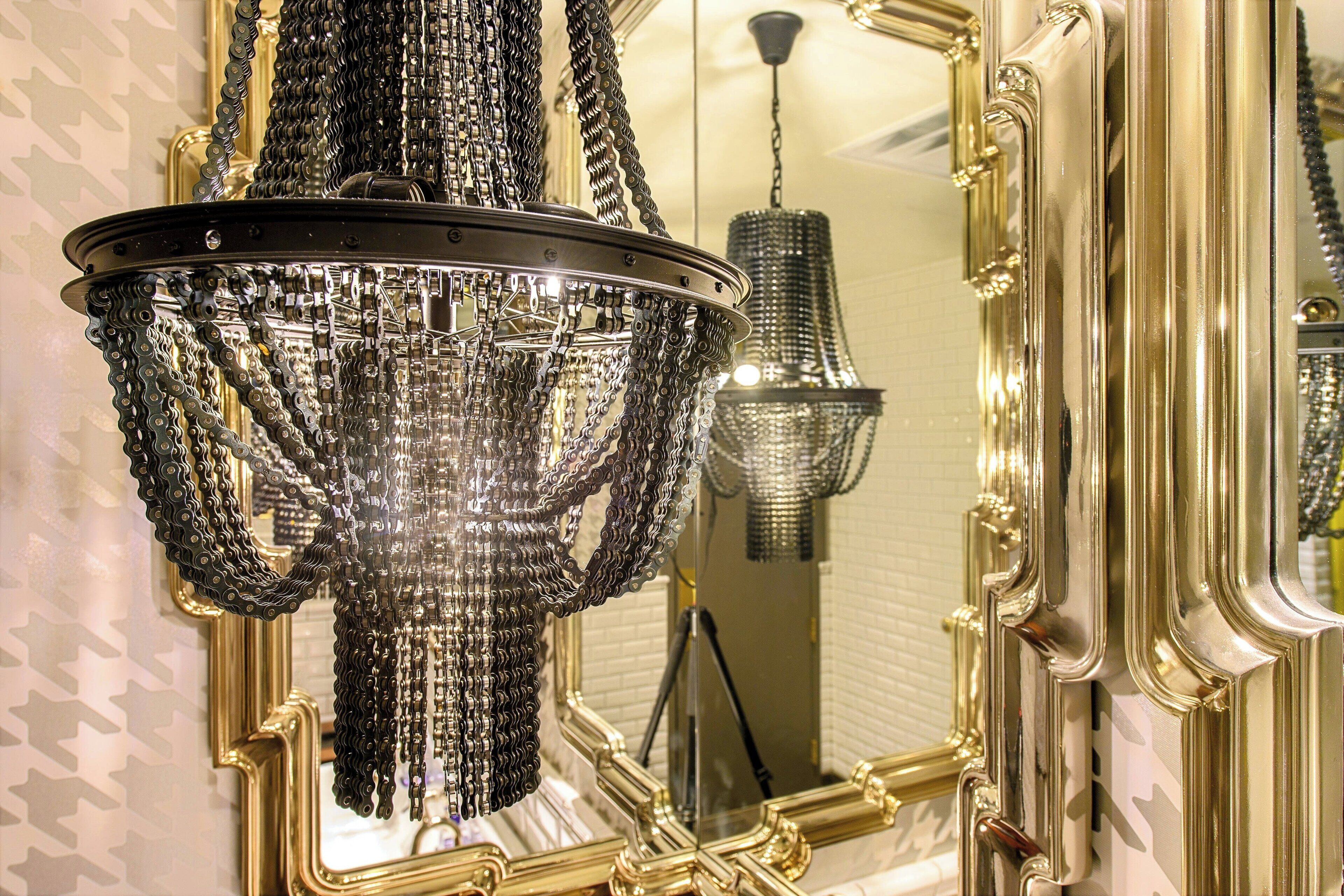 A chandelier with multiple chains and a mirror with ornate gold framing.