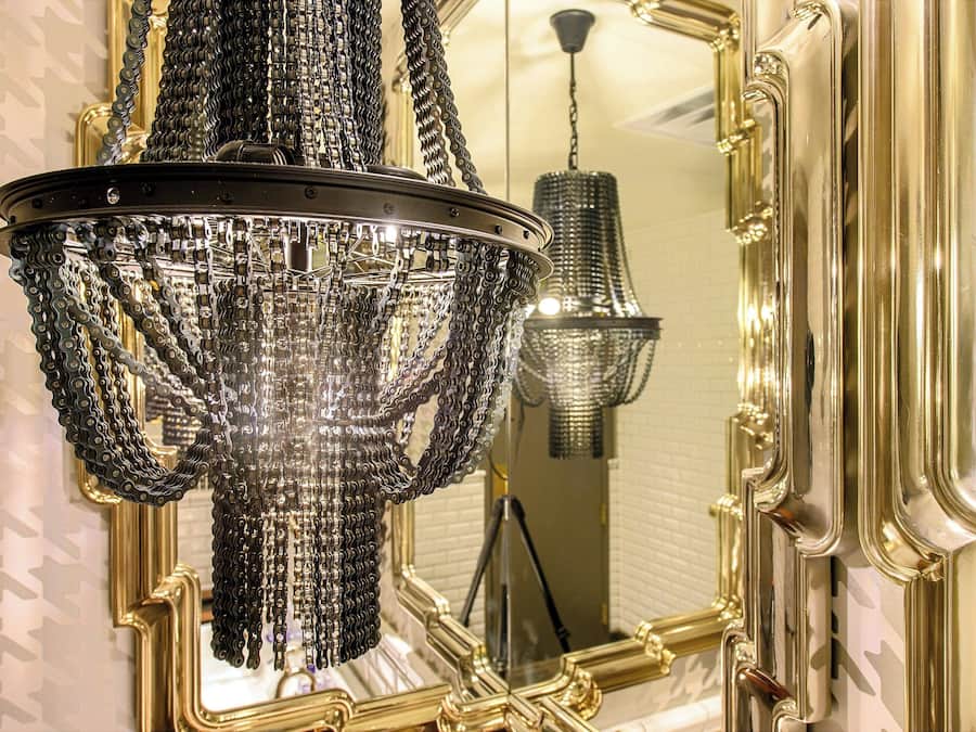 A chandelier with multiple chains and a mirror with ornate gold framing.