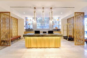 A modern reception desk with a marble top, three black laptops, and a golden light-up base. - WATERMARK Baton Rouge, Autograph Collection (Baton Rouge)