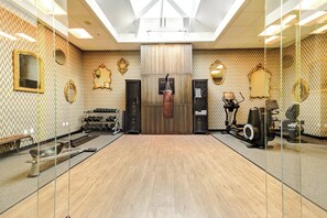 A gym with mirrored walls, exercise equipment, and a central punching bag. - WATERMARK Baton Rouge, Autograph Collection (Baton Rouge)