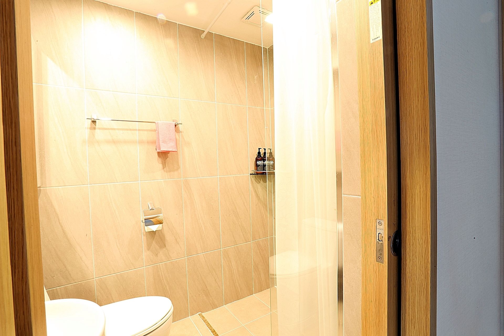 A modern bathroom with a toilet, a towel rack, and a shower area.