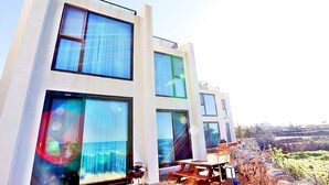 A modern building with large windows and a picnic table outside. - JejuSorang (Jeju City)