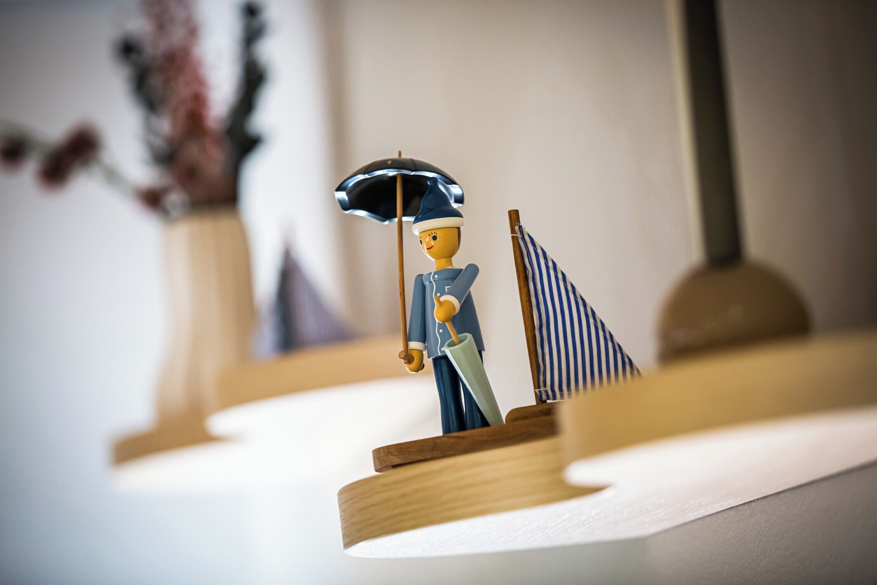 A miniature model of a person holding an umbrella and a flag on a shelf.