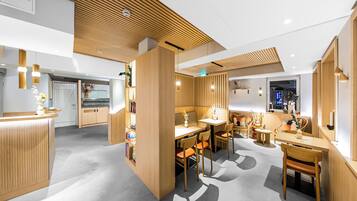 A modern interior with wooden paneling, a reception desk, and a dining area with chairs and tables.