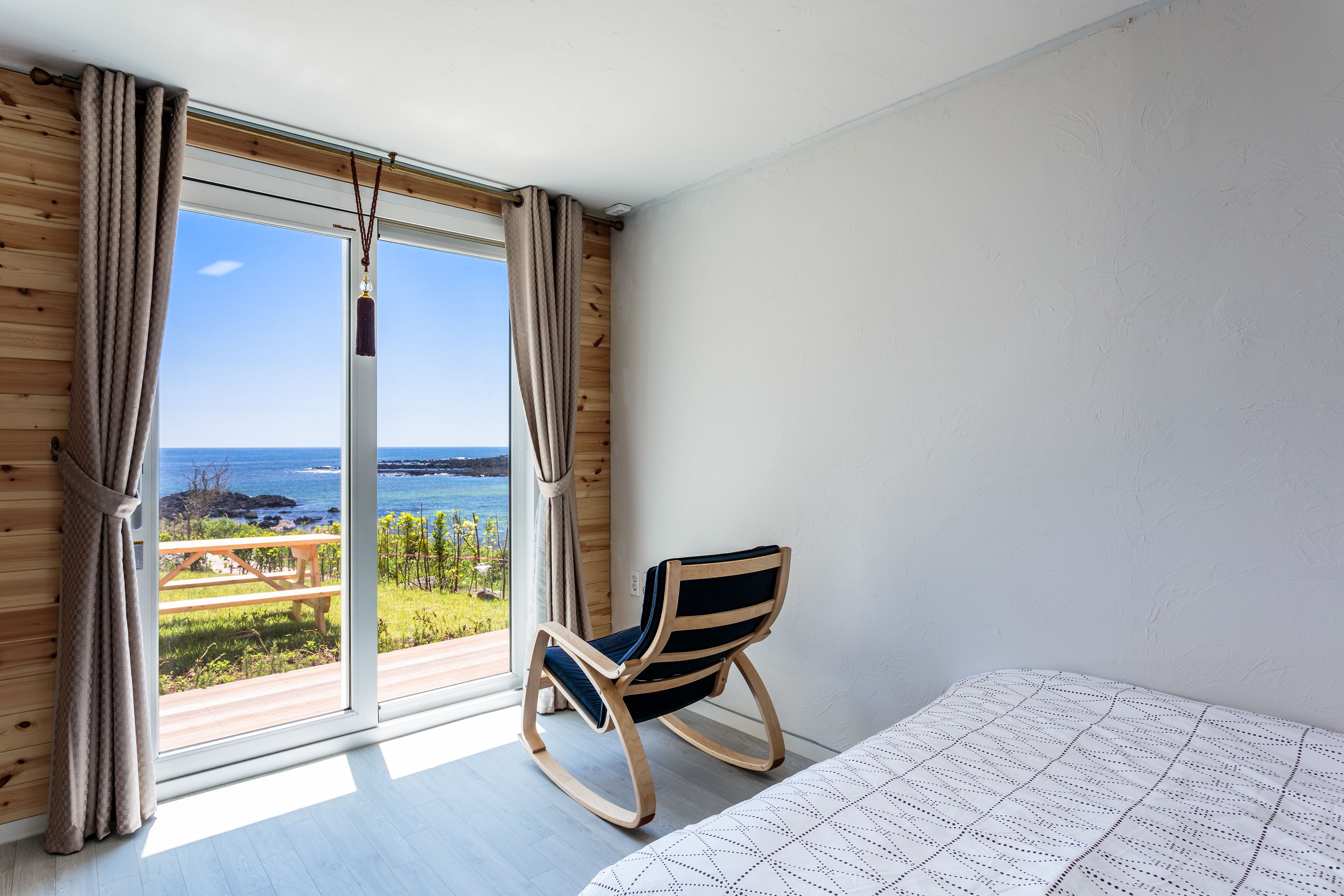 A room with a large sliding glass door leading to a balcony with a view of the sea.