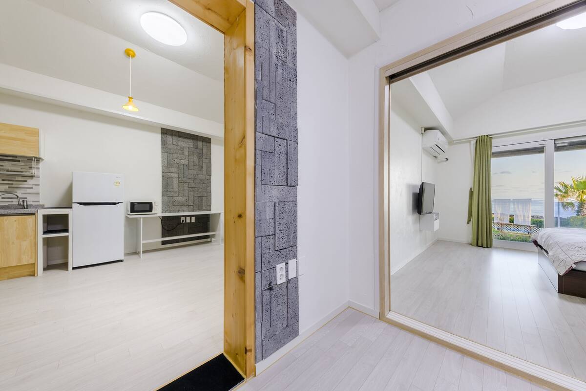 A modern apartment with a kitchen, a dining area, a bedroom with a large window, and a balcony.