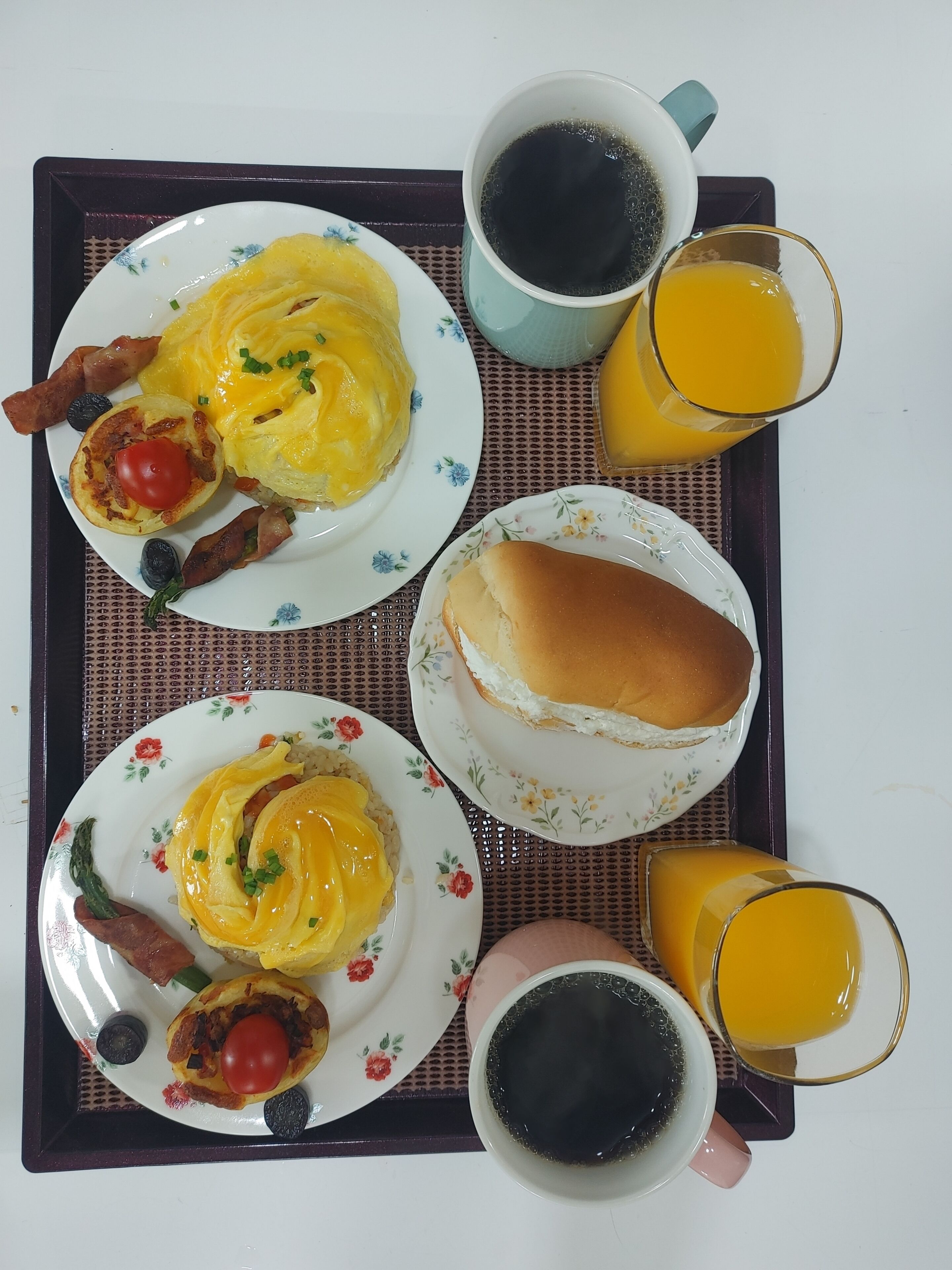 A tray with breakfast items including eggs, bacon, and toast, accompanied by cups of coffee and orange juice.