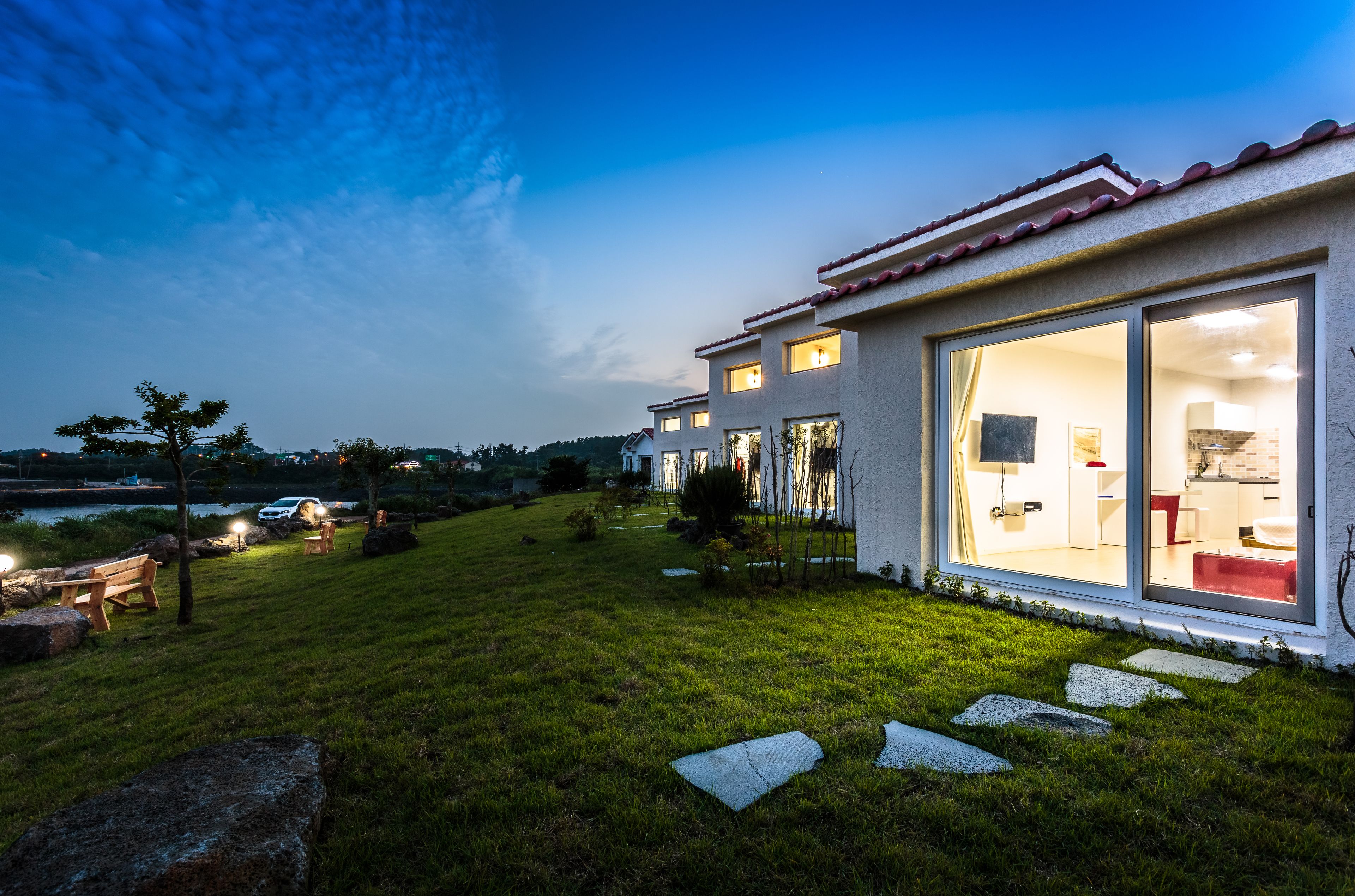 A modern house with large glass doors, a well-maintained lawn, and outdoor seating.