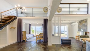 A spacious living area with a staircase, a dining area, and a view of the outdoors. - Jeju Turning Point (Seogwipo)