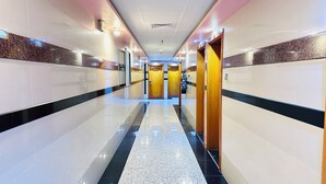 A hotel corridor with a polished floor, mirrored walls, and a central door leading to a room. - Palette San Marino Hotel (Dubai)