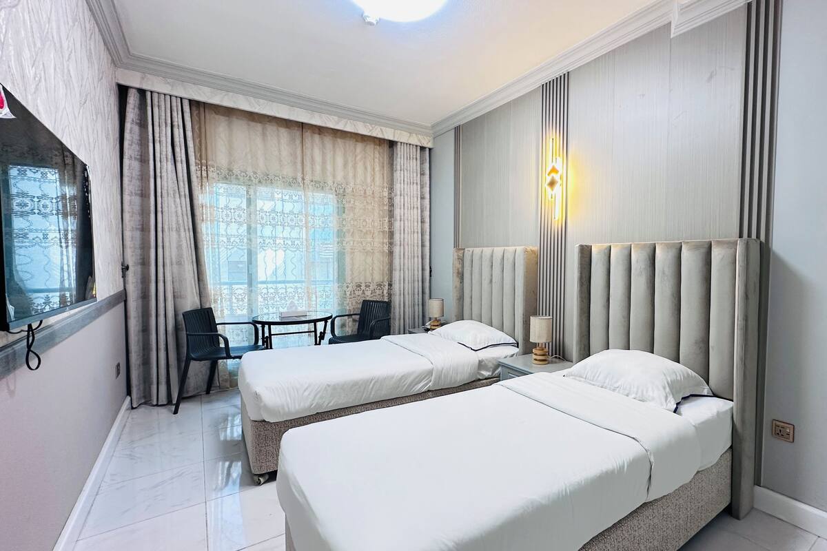 A hotel room with two beds, a desk, and a chair.