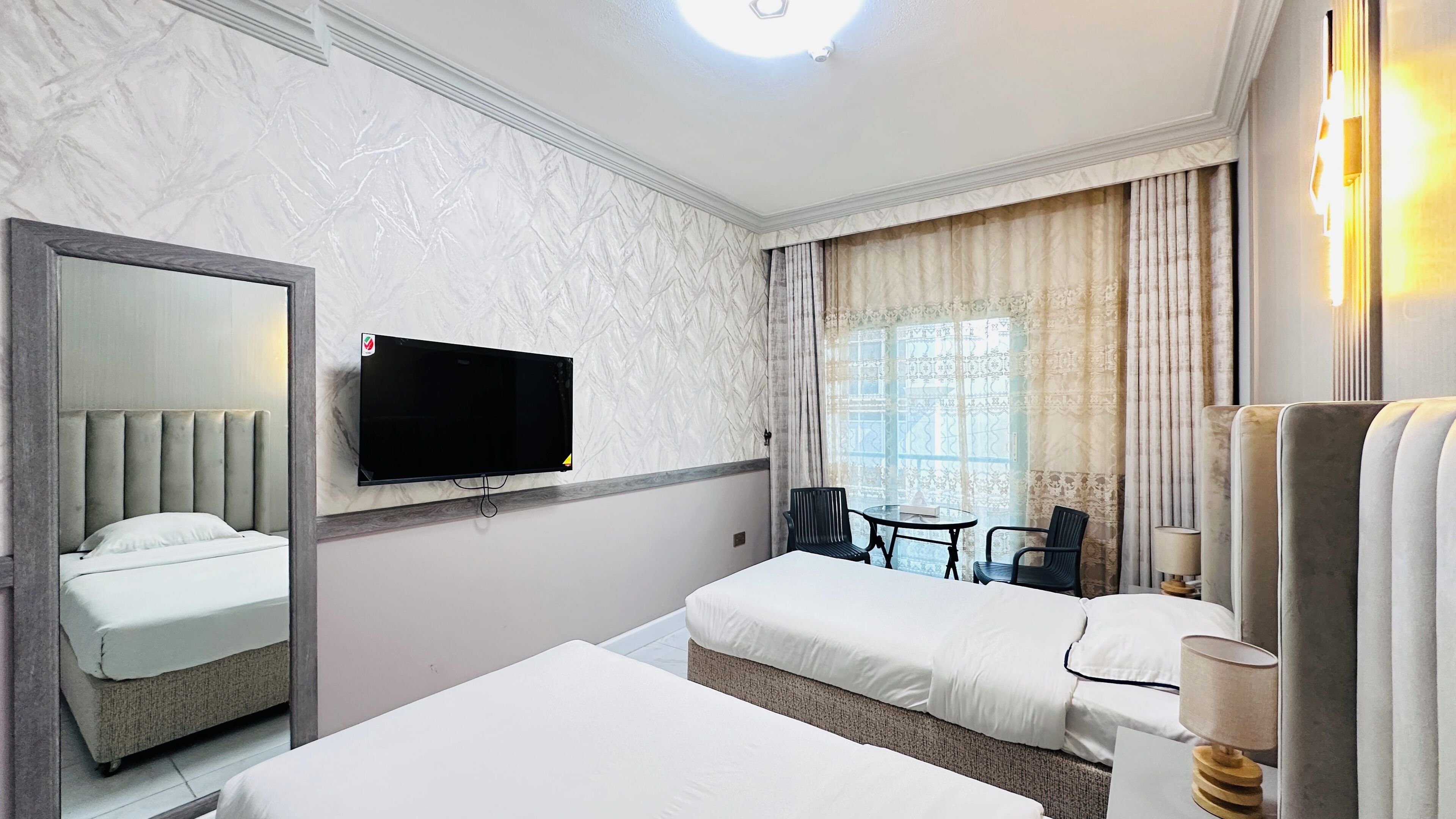 A hotel room with two beds, a flat-screen TV, a small table, and a chair.