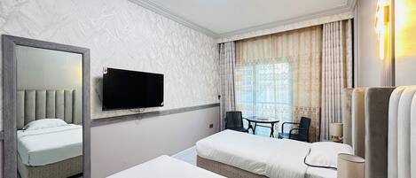 A hotel room with two beds, a flat-screen TV, a small table, and a chair.
