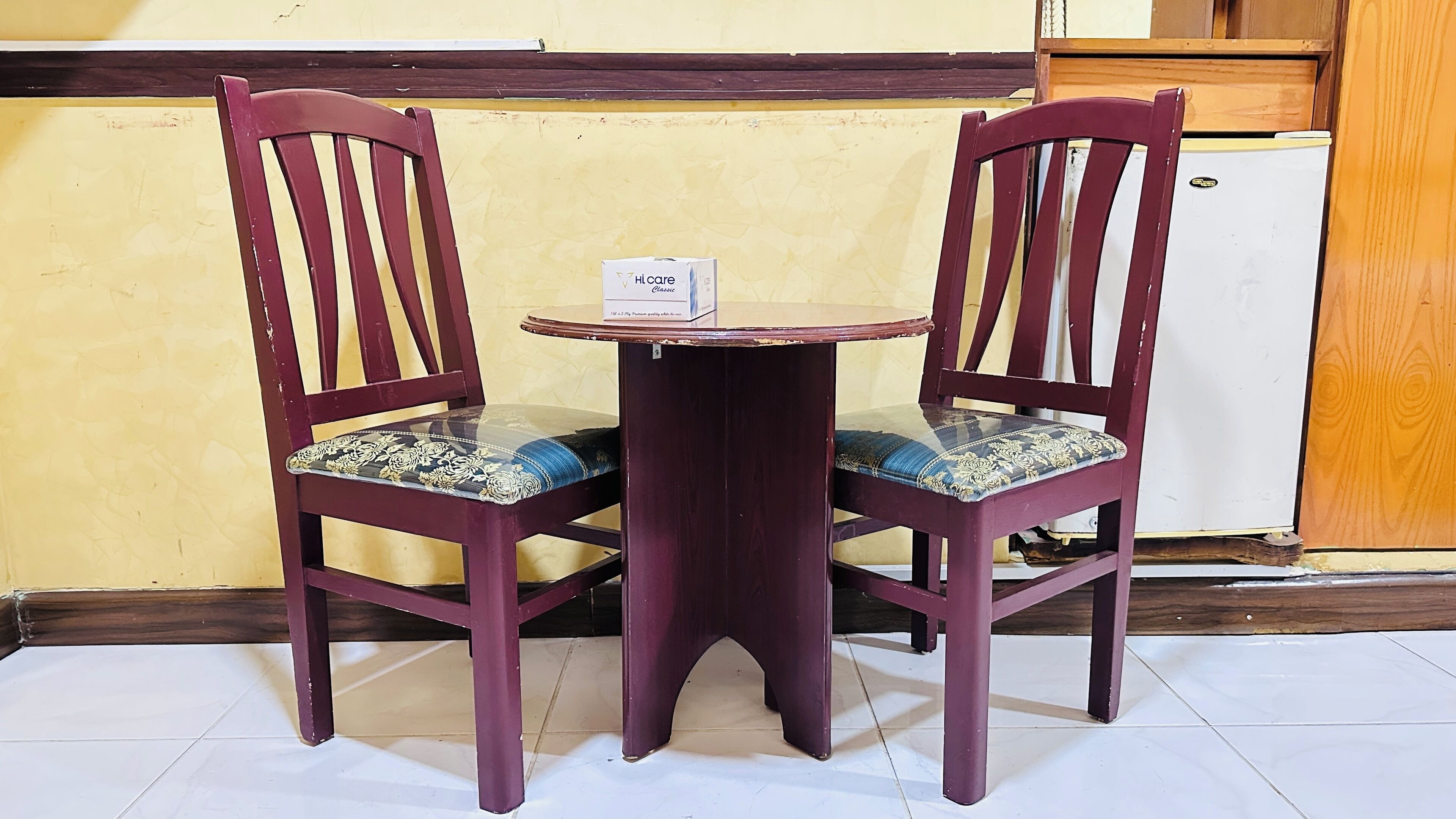 A small round table with two chairs, each with a cushioned seat and backrest.
