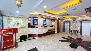 A hotel reception area with a marble floor, a reception desk, and two elevators. - Palette San Marino Hotel (Dubai)