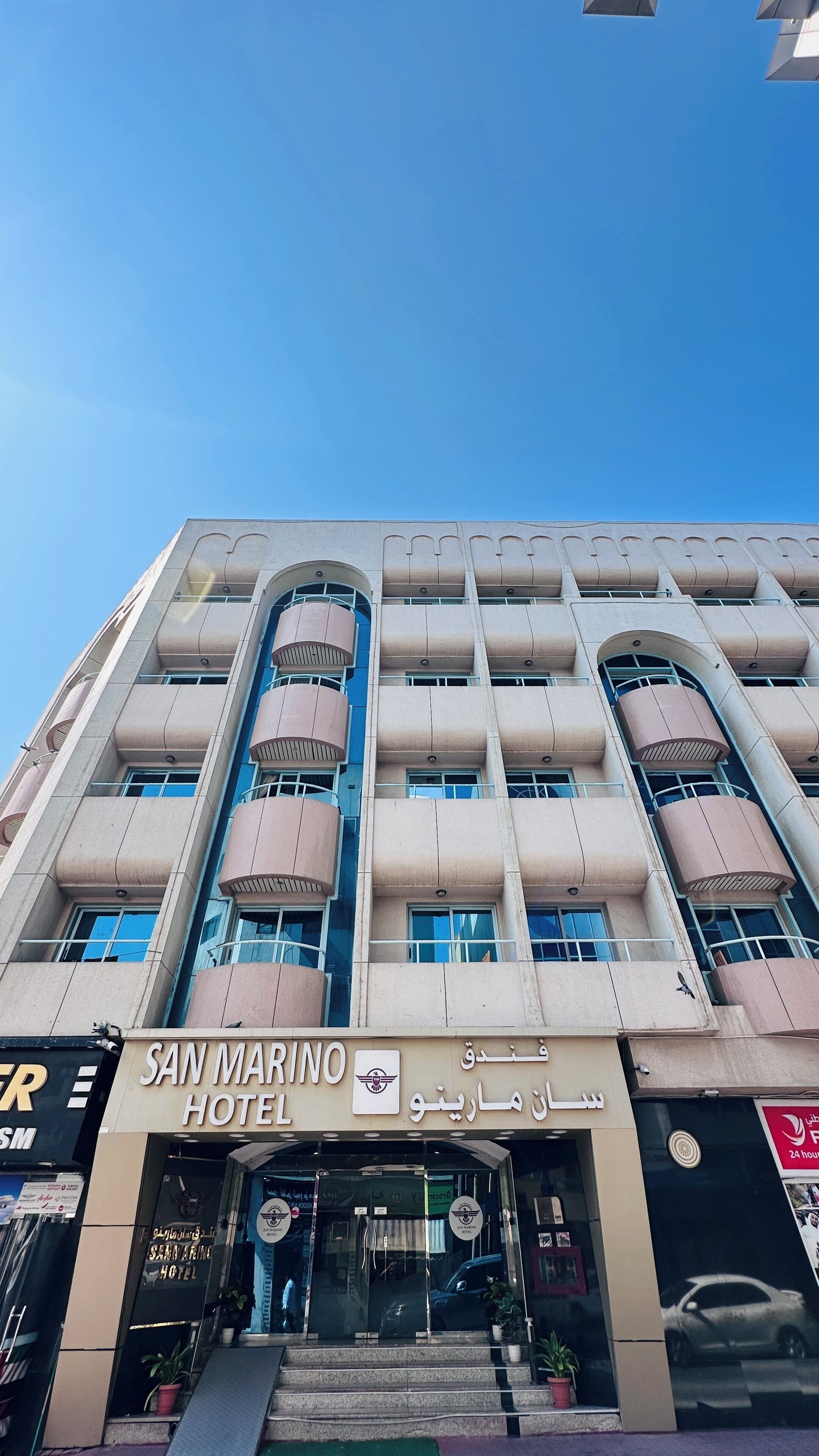 A multi-story hotel with a modern facade, featuring balconies and large windows.