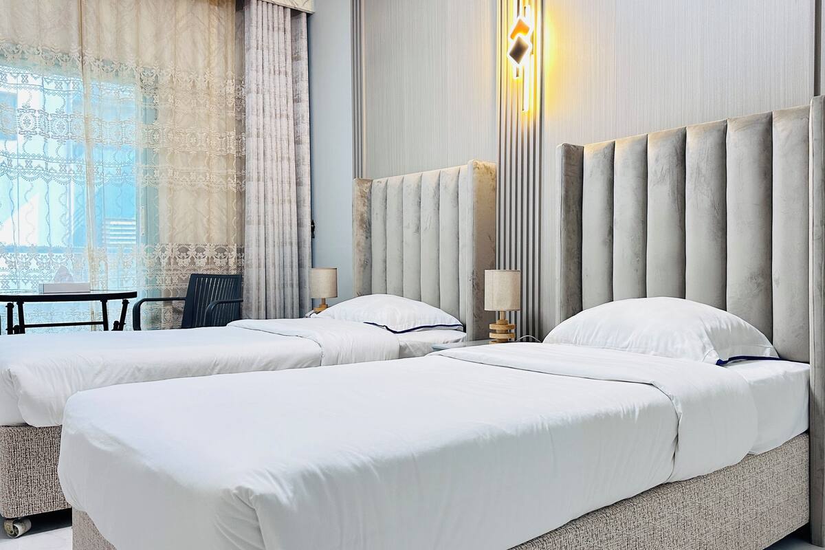 A hotel room with two beds, a desk, and a chair.