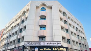 A multi-story hotel with a modern architectural design, featuring balconies and a prominent entrance. - Palette San Marino Hotel (Dubai)